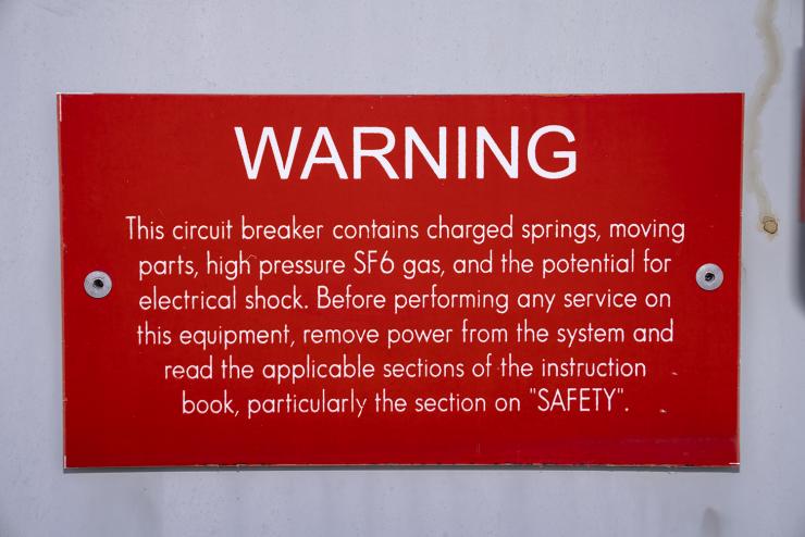 TESLA High-Voltage Circuit Breaker Warning Sign A warning sign on a high-voltage circuit breaker mentioning sulfur hexafluoride (SF6). SF6 has a global warming potential 23,900