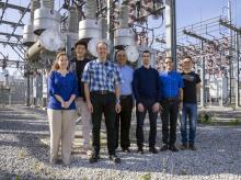 The TESLA (Tough and Ecological Supercritical Line Breaker for AC) team in front of high-voltage circuit breakers. 